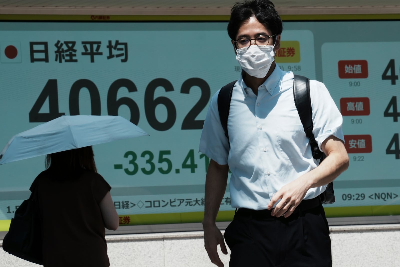 A person walks in front of an electronic stock board showing Japan's Nikkei index at a securities firm Tuesday, July 29, 2025, in Tokyo. (AP Photo/Eugene Hoshiko)