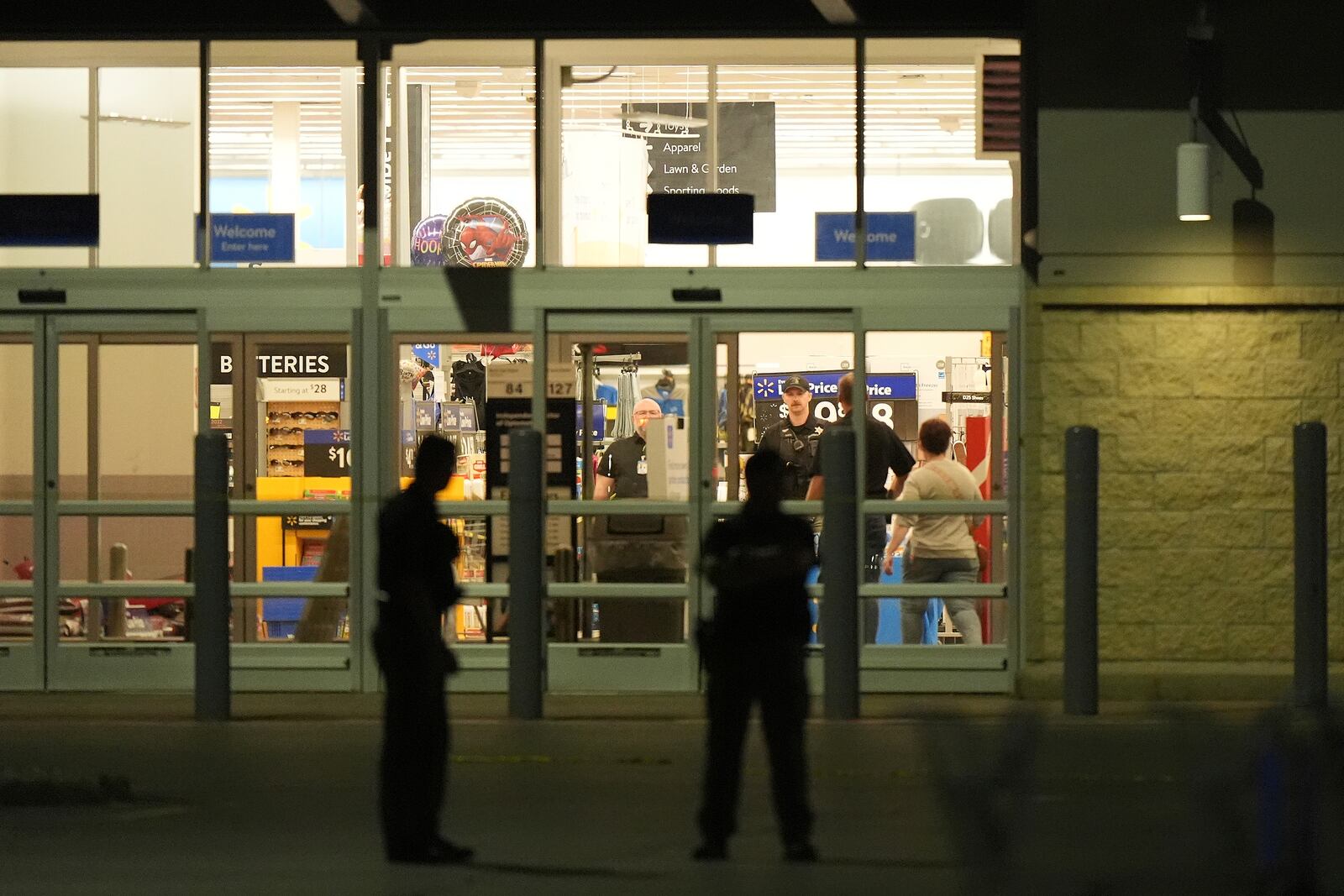 Law enforcement officers are seen stationed outside a Walmart where 11 people were stabbed in a violent attack Saturday, July 26, 2025, in Traverse City, Mich (AP Photo/Ryan Sun)