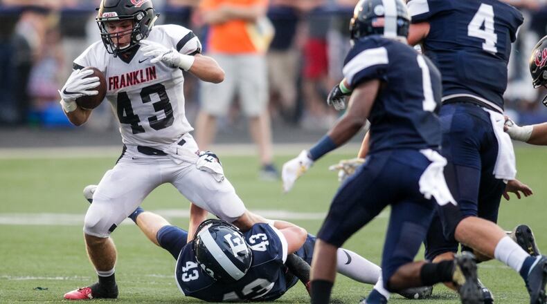 Edgewood’s Kory McCall tries to tackle Franklin’s Gage Johnson as he carries the ball during their Aug. 31 game at Kumler Field in St. Clair Township. The host Cougars won 28-9. NICK GRAHAM/STAFF