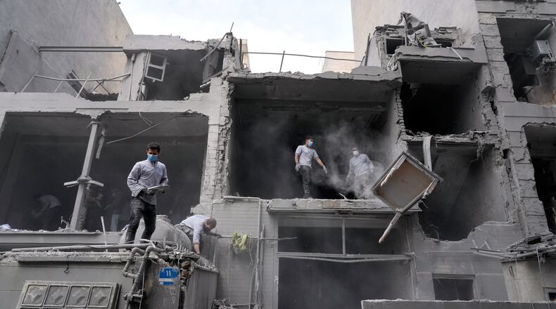 Volunteers clean debris from a residential building damaged when a nearby police station was hit Friday in a U.S.-Israeli strike in Tehran, Iran, Sunday, March 15, 2026. (AP Photo/Vahid Salemi)