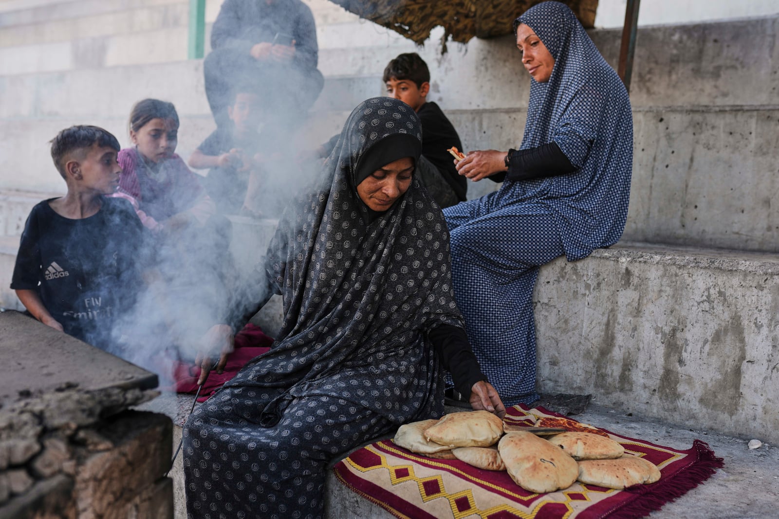 Displaced Palestinians prepare bread in a makeshift oven in Gaza City, Monday, May 5, 2025. (AP Photo/Jehad Alshrafi)