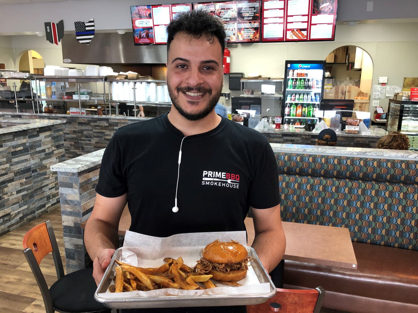Prince Ahmed delivers a pulled pork sandwich and French fries at Prime BBQ Smokehouse in Monroe. RICK McCRABB/STAFF