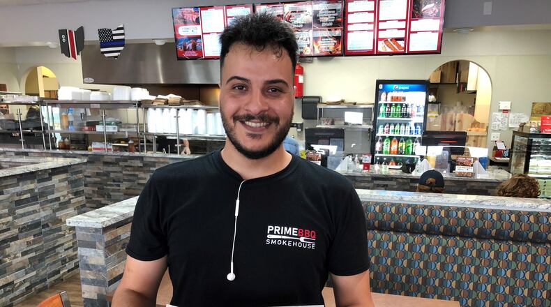 Prince Ahmed delivers a pulled pork sandwich and French fries at Prime BBQ Smokehouse in Monroe. RICK McCRABB/STAFF