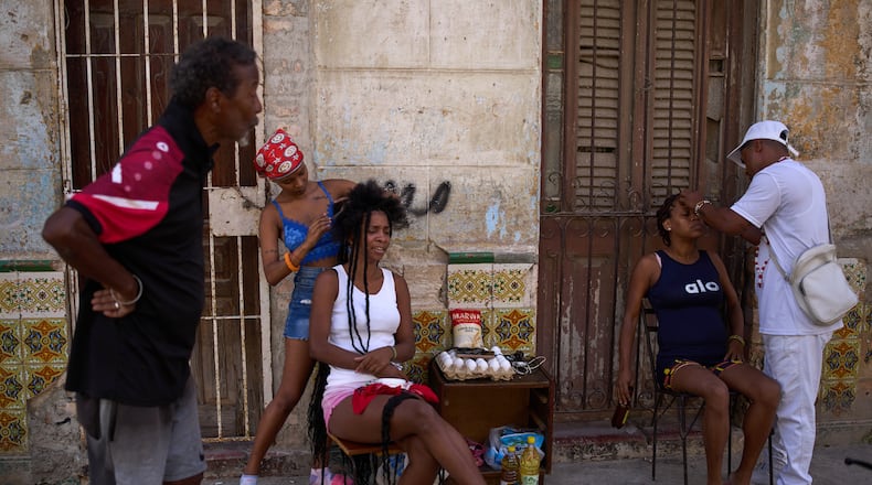 Hairdressers style the hair of their clients in the open air during a blackout in Havana, Cuba, Thursday, March 5, 2026. (AP Photo/Ramon Espinosa)