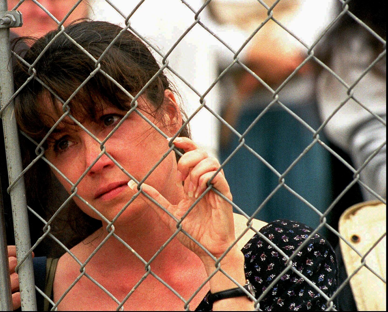 FILE - Karen Ellison looks through a chain link fence at a memorial service for rescue workers and volunteers at the Alfred P. Murrah Federal Building in Oklahoma City on May 5, 1995. (AP Photo J. Pat Carter, File)
