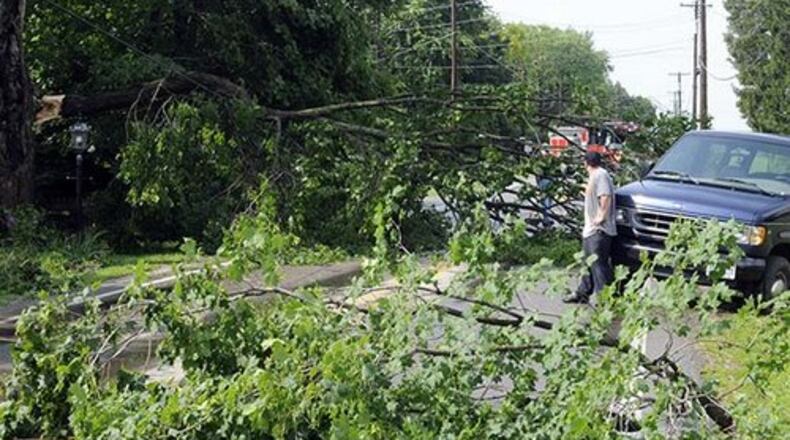 FILE PHOTO A man waits by his van after getting stuck along Medway-New Carlisle Pike when he tried to drive around a large tree branch that blocked the roadway during a severe thunderstorm that blew through the area with high winds and rain.