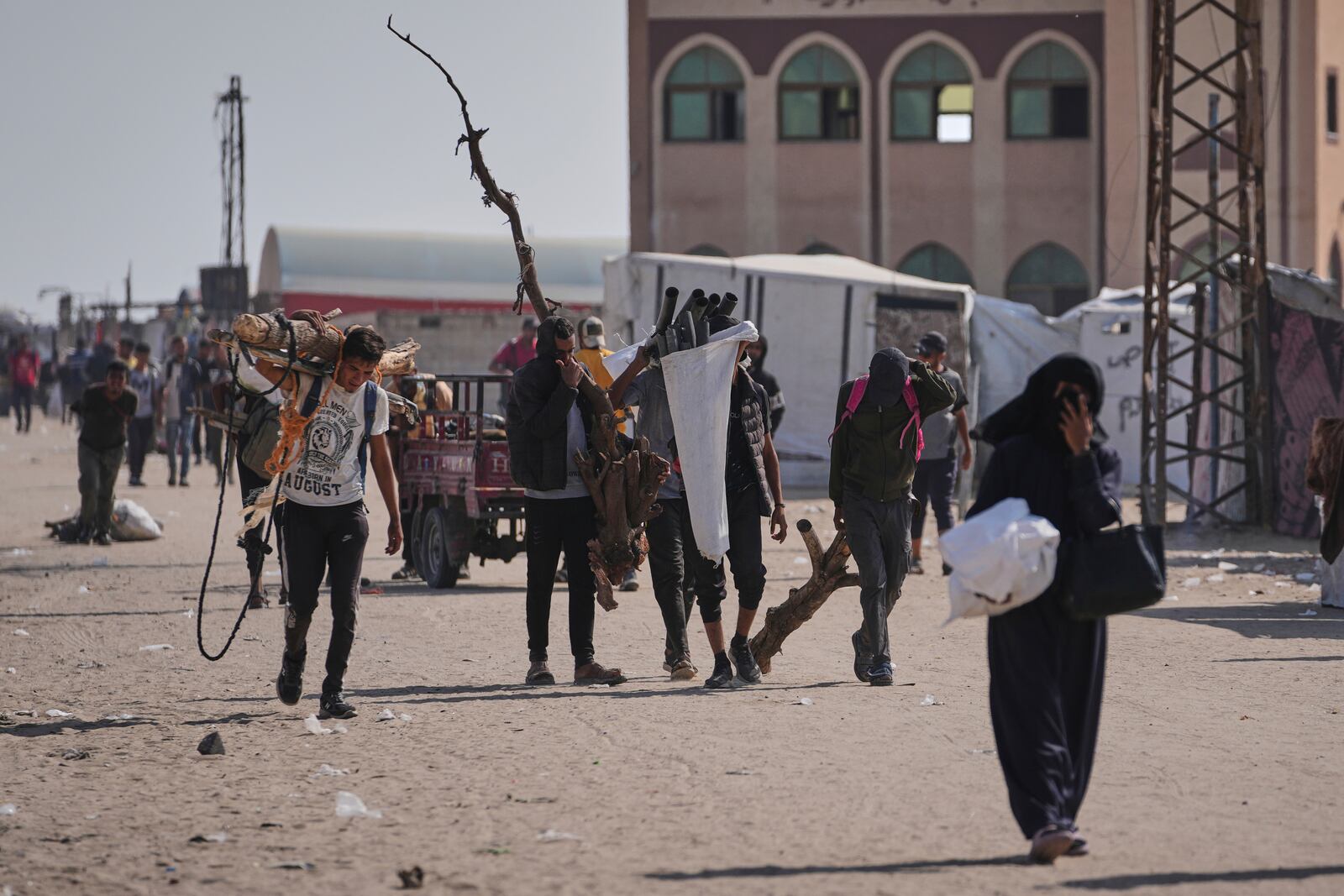 Displaced Palestinians carrying wood and other items in Rafah, southern Gaza Strip on Saturday, June 7, 2025. (AP Photo/Jehad Alshrafi)