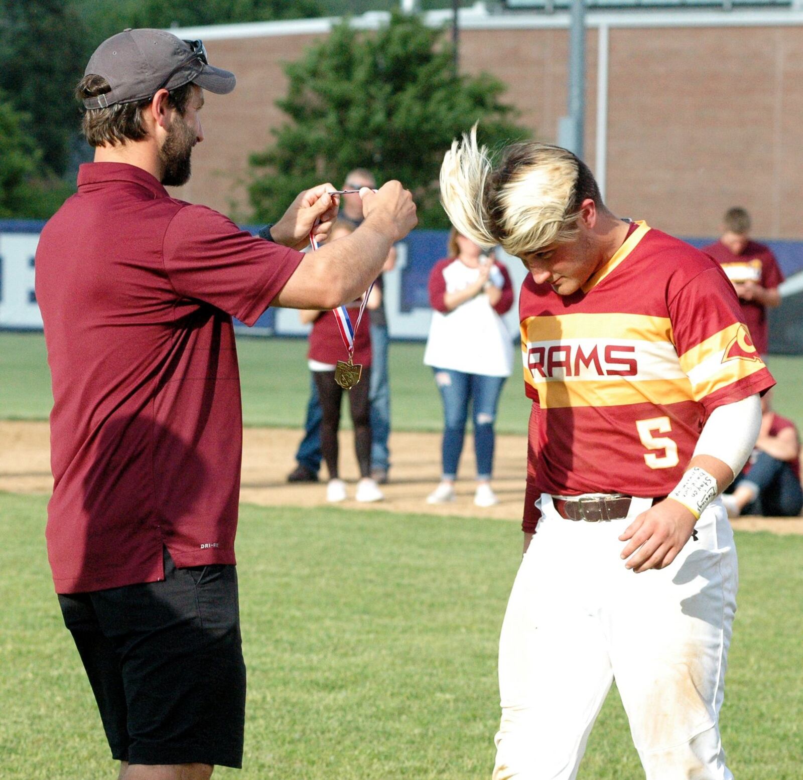 Ethan Mills of Ross gets his district championship medal from RHS athletic director Jake Richards on Thursday after a Division II district baseball final against Springfield Kenton Ridge at Hamilton’s Stang Field. Ross won 1-0. RICK CASSANO/STAFF