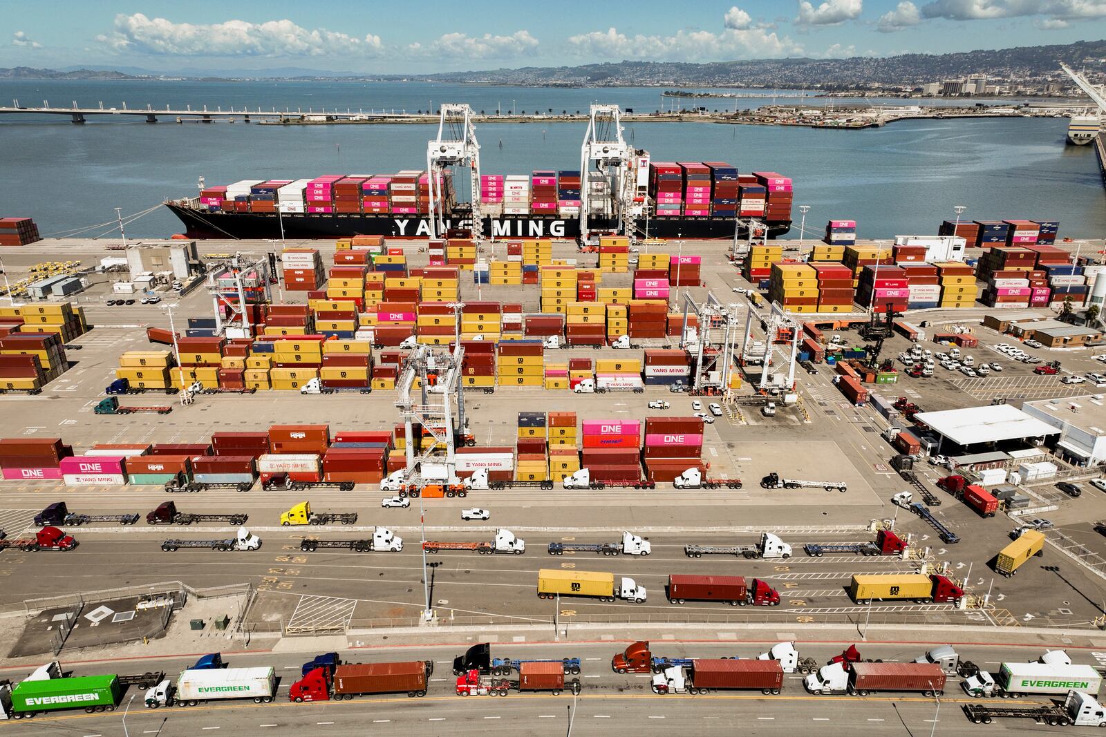A ship is docked with cargo as trucks are shown at The Port of Oakland in Oakland, Calif., Thursday, April 3, 2025. (Bronte Wittpenn/San Francisco Chronicle via AP)