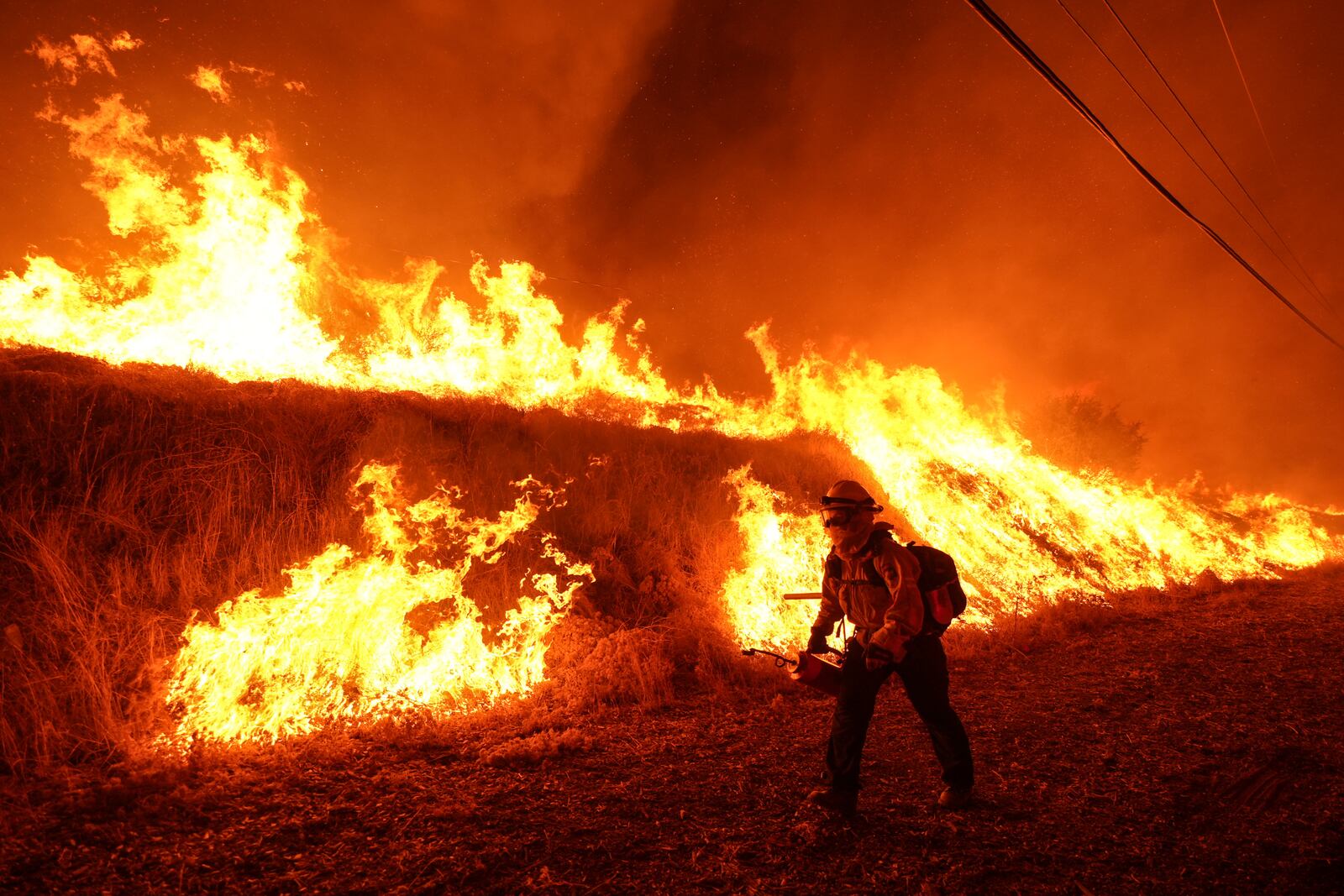 FILE - A firefighter carries a drip torch as he ignites a backfire against the Hughes Fire burning along a hillside in Castaic, Calif., Jan. 22, 2025. (AP Photo/Jae C. Hong, File)
