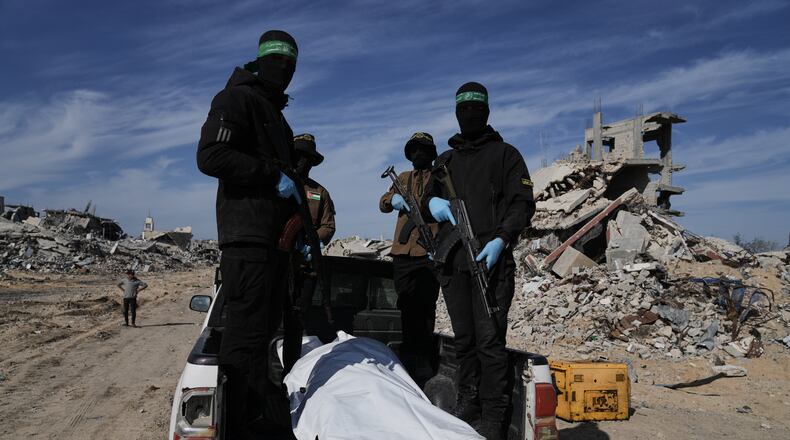 Islamic Jihad and Hamas militants carry a white body bag that is believed to be the remains of a deceased hostage, in the town of Beit Lahiya in northern Gaza Strip, Wednesday, Dec. 3, 2025. (AP Photo/Jehad Alshrafi).