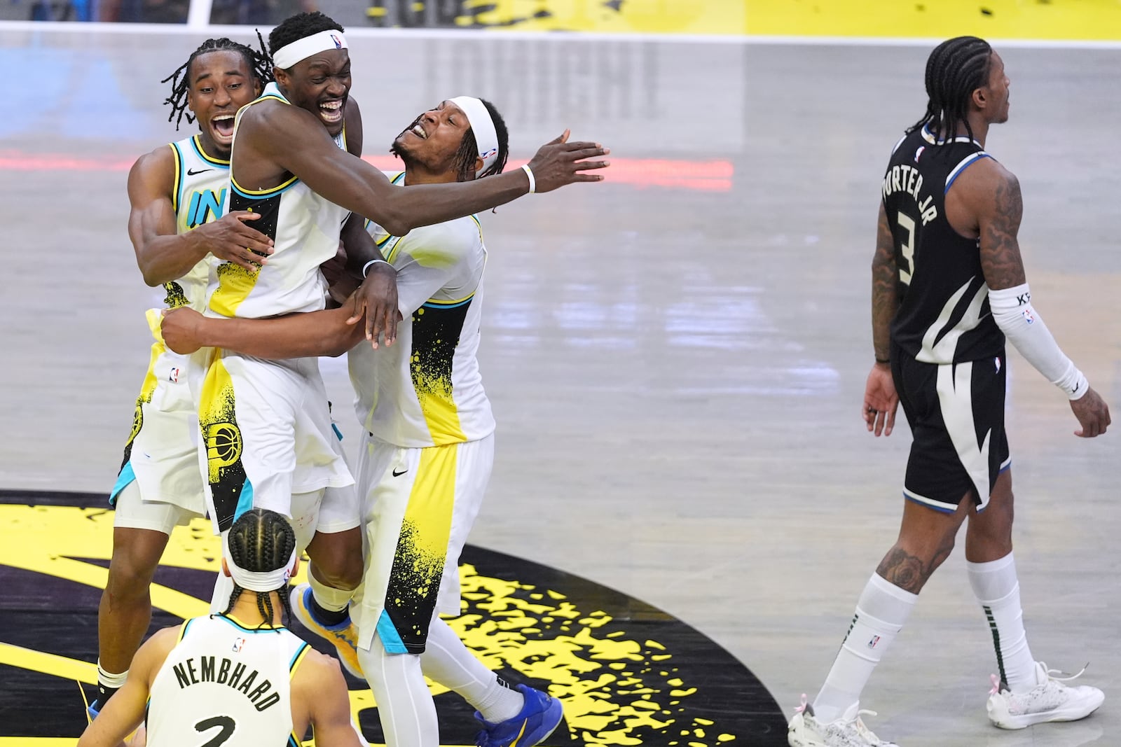 Indiana Pacers teammates Aaron Nesmith, left, Pascal Siakam, center, and Myles Turner, right, celebrate the team's win after overtime in Game 5 of an NBA basketball first-round playoff series as Milwaukee Bucks guard Kevin Porter Jr. (3) walks off the court in Indianapolis, Tuesday, April 29, 2025. (AP Photo/Michael Conroy)