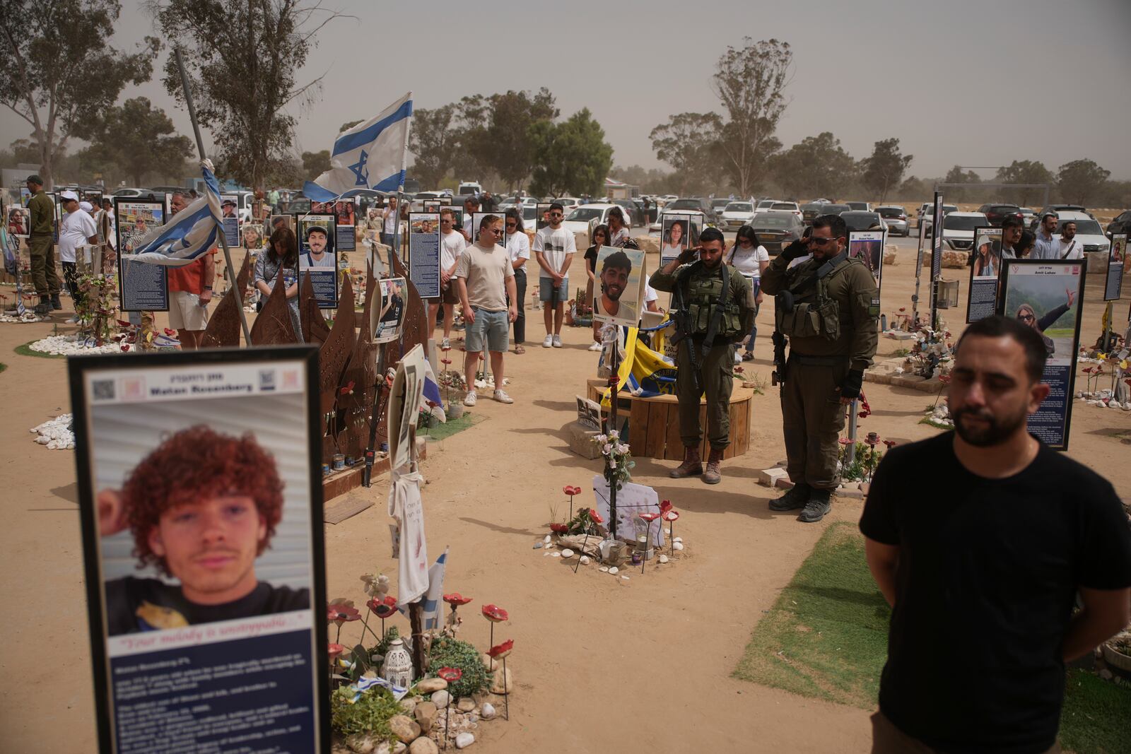 People stand still to observe two minutes of silence as air raid sirens sound marking the Israel's annual Memorial Day at the site of Oct. 7, 2023 attack by Hamas militants at the Nova music festival near Kibbutz Reim, southern Israel, Wednesday, April 30, 2025. (AP Photo/Ohad Zwigenberg)