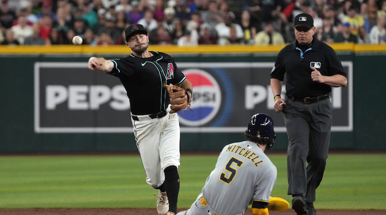 Arizona Diamondbacks second baseman Garrett Hampson turns the double play while avoiding Milwaukee Brewers' Garrett Mitchell (5) on a ball hit by Joey Ortiz in the second inning during a baseball game, Saturday, April 12, 2025, in Phoenix. (AP Photo/Rick Scuteri)