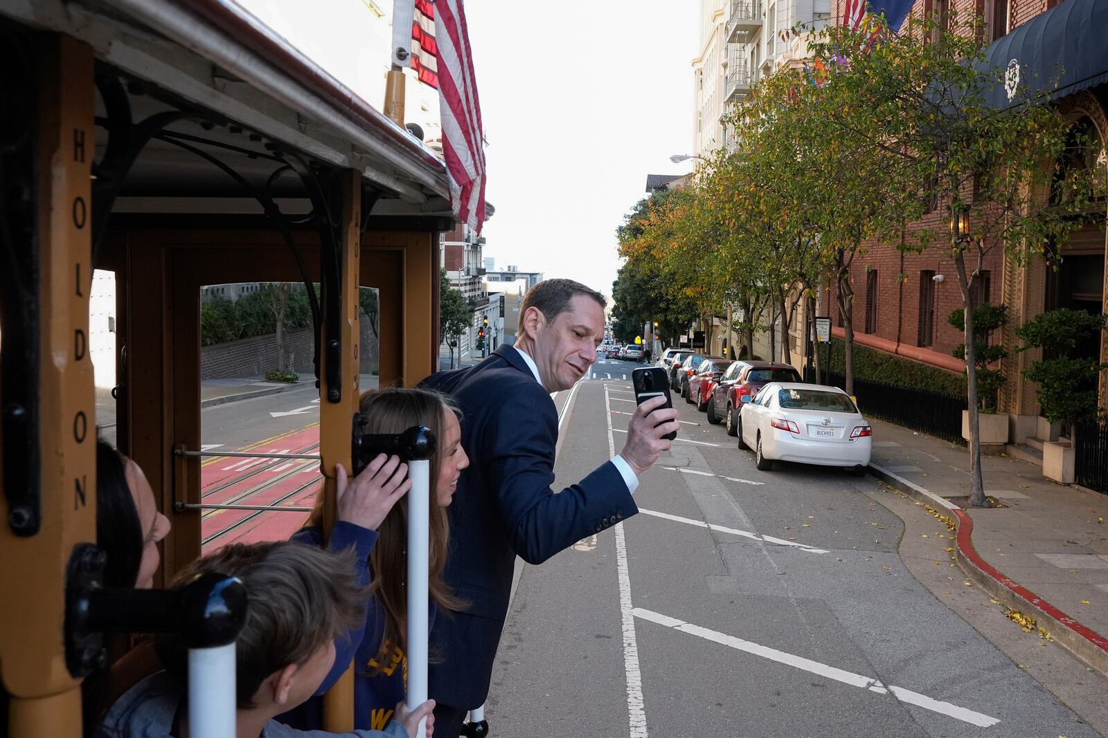 FILE - Mayor-elect Daniel Lurie, right, takes a photograph of his family while riding a cable car, before being inaugurated into office Wednesday, Jan. 8, 2025, in San Francisco. (AP Photo/Godofredo A. Vásquez, File)