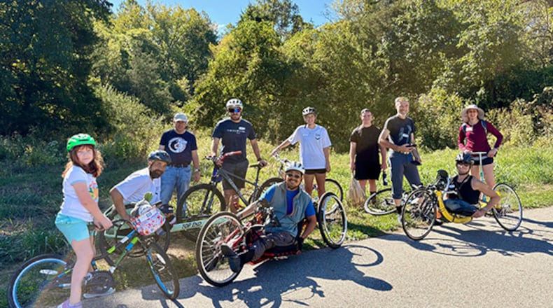 The scenic woodland surrounding Miami University’s main campus is being opened as a natural classroom for those who overcome mobility challenges thanks to a Miami instructor who is an adaptive athlete. The first Adaptive Nature Walk on Wheels was recently conducted at the Oxford campus by hand cyclist Yoshi Tomoyasu (front center), associate professor of biology at Miami, who came up with the idea. (Provided)