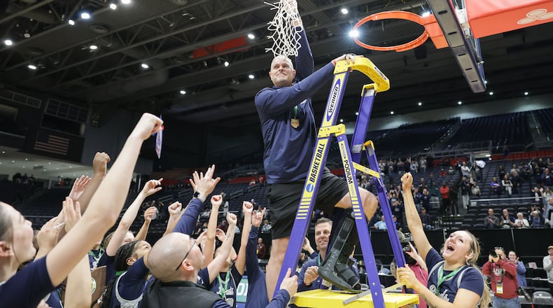 Fairmont coach Jeremy Finn hoists the net after cutting it down following the Firebirds' 61-55 overtime win over Princeton in the Division I state final on Saturday, March 14 at University of Dayton Arena. Finn is in his eighth season at the helm. BRYANT BILLING / STAFF