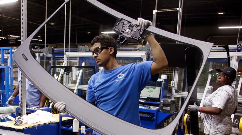 Workers at Fuyao Glass America finish an automobile windshield in the Moraine plant. Fuyao currently employs 2,300 workers and expects to need 700 more within three years. TY GREENLEES / STAFF