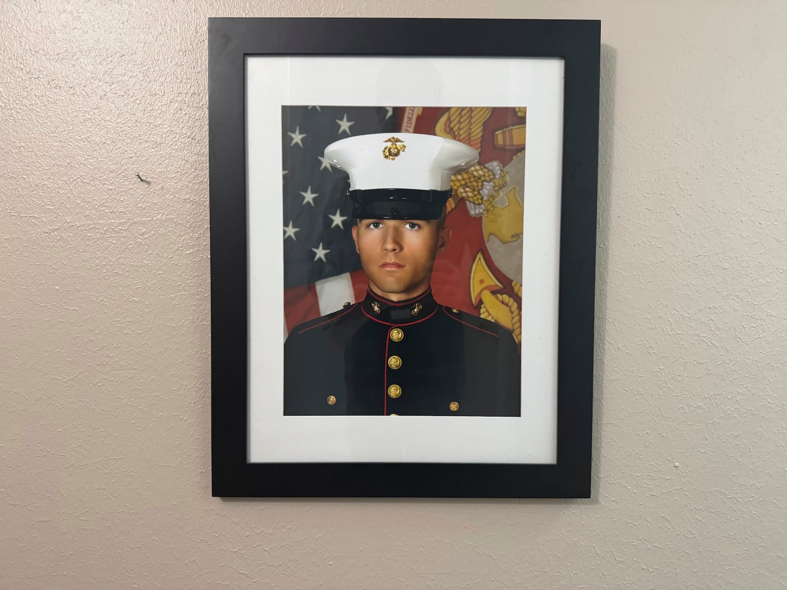 A portrait of Adrian Clouatre during his years of service with the U.S. Marine Corps hangs on the wall of his family's home in Baton Rouge on Tuesday, June 17, 2025. (AP Photo/Jack Brook)