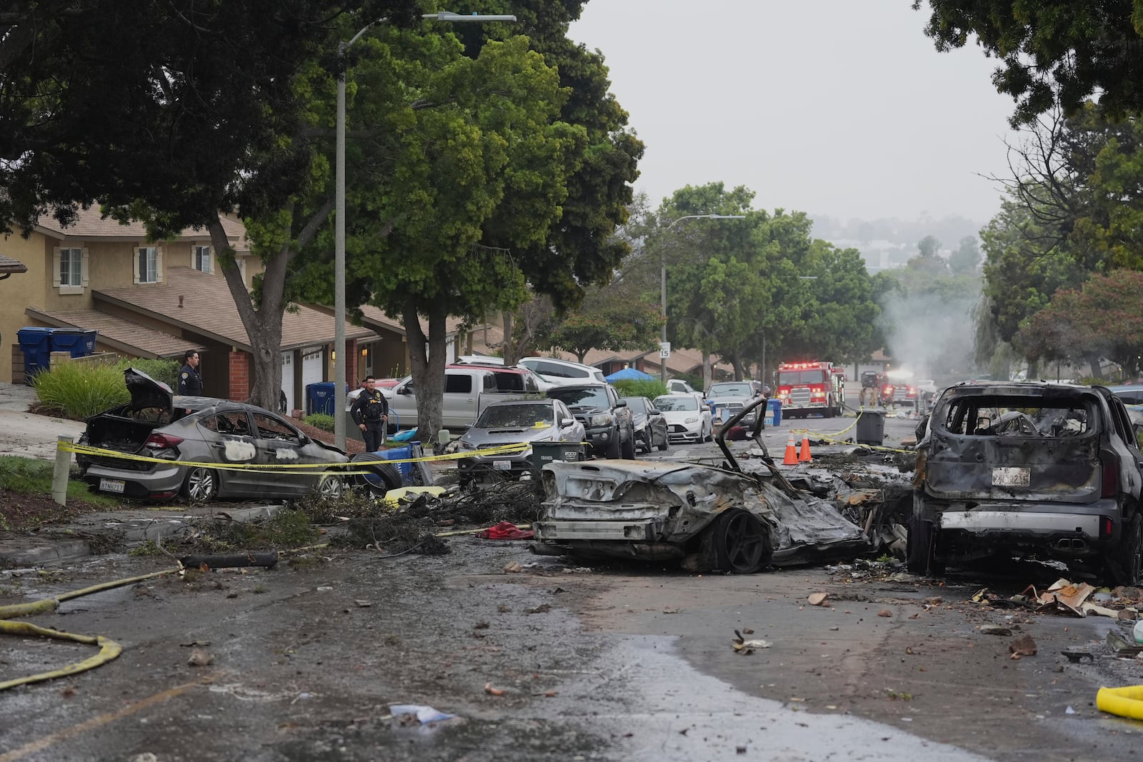 Authorities work the scene where a small plane crashed into a San Diego neighborhood, setting several homes on fire and forcing evacuations along several blocks early Thursday, May 22, 2025. (AP Photo/Gregory Bull)