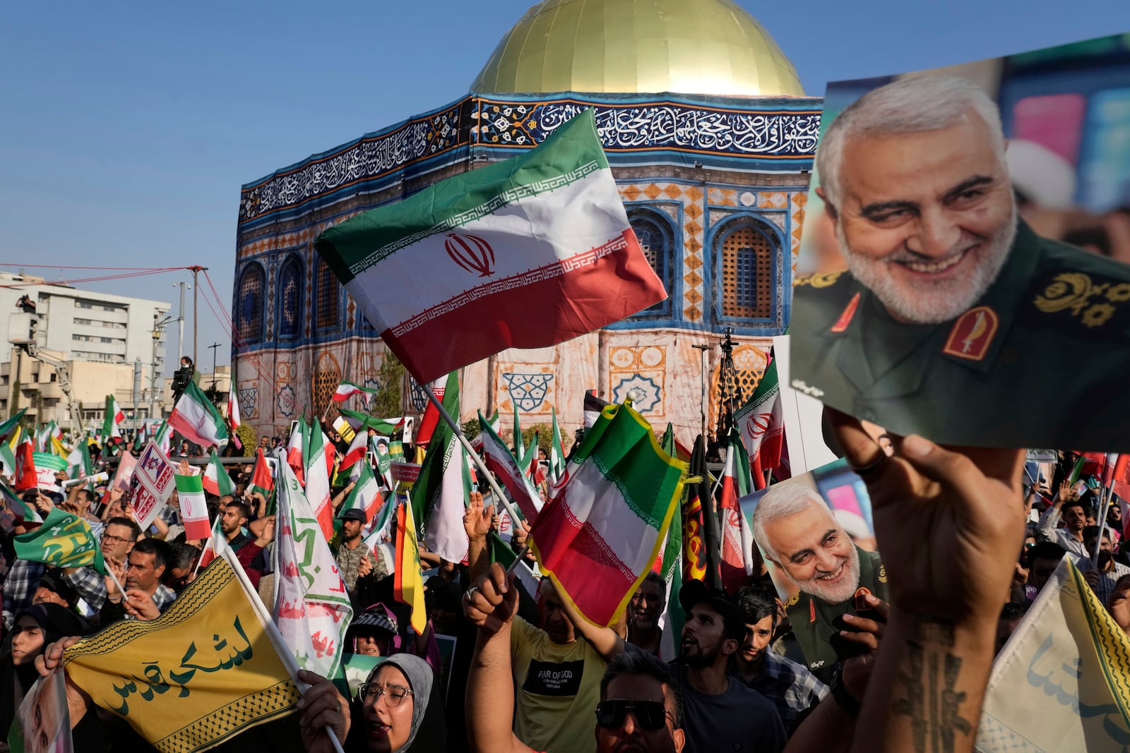 Demonstrators wave Iranian flags and hold posters of the late Iranian Revolutionary Guard Gen. Qassem Soleimani, who was killed in a U.S. strike in Iraq in 2020, in front of a model of Jerusalem's Dome of the Rock mosque during a rally marking the Muslim Shiite holiday of Eid al-Ghadir, which commemorates the Prophet Muhammad naming his successor, Ali, who is revered as the first Shiite imam, in Tehran, Iran, Saturday, June 14, 2025. (AP Photo/Vahid Salemi)