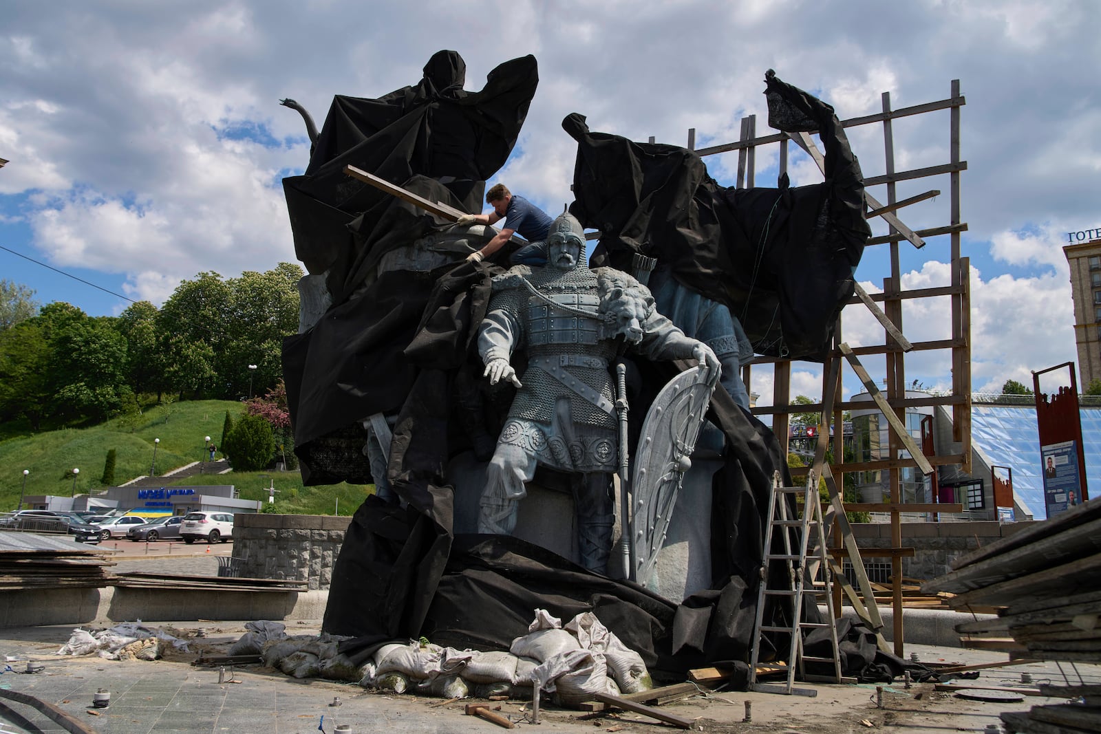 Municipal workers remove the cover that protected a monument of Kyiv legendary founders from Russian missile attacks on the fourth year of Russia-Ukraine war on the country's main square in Kyiv, Ukraine, Wednesday, May 21, 2025. (AP Photo/Efrem Lukatsky)(