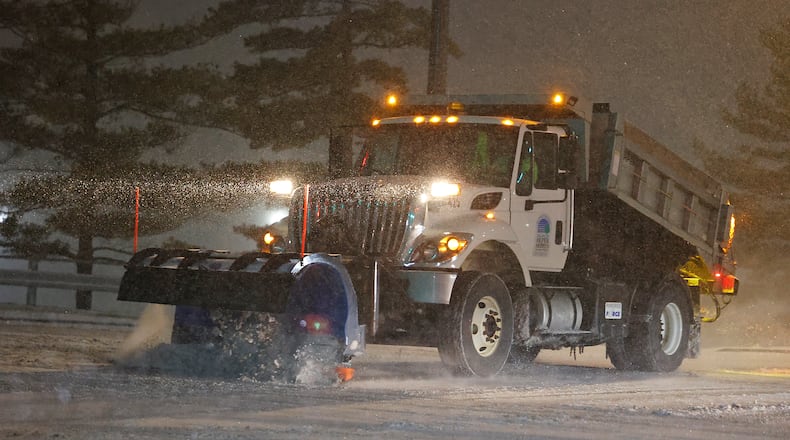 A snow plow cleans off the intersection of Taylorsville Road and Old Troy Pike in Huber Hights Sunday evening. BILL LACKEY/STAFF