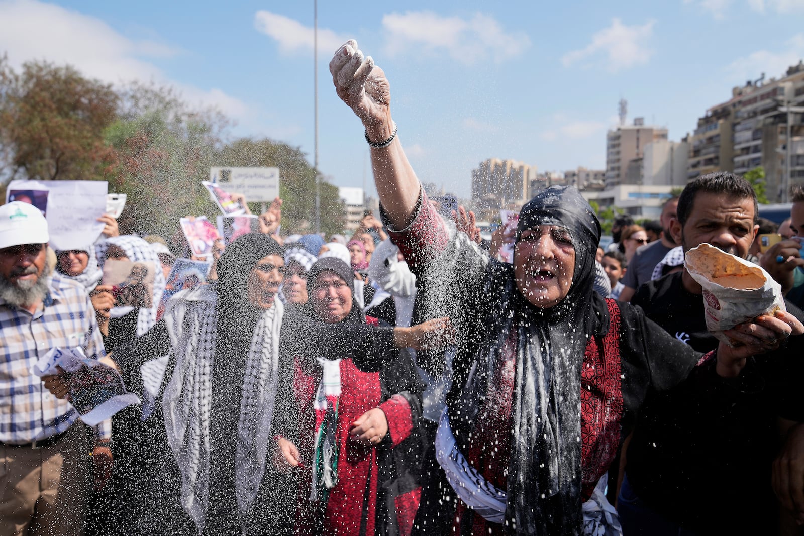 A woman throws flour, as she protests outside the Egyptian Embassy in Beirut, Lebanon, Wednesday, July 23, 2025, during a demonstration against the Israeli war and what they say starvation of civilians in the Gaza Strip. (AP Photo/Hussein Malla)