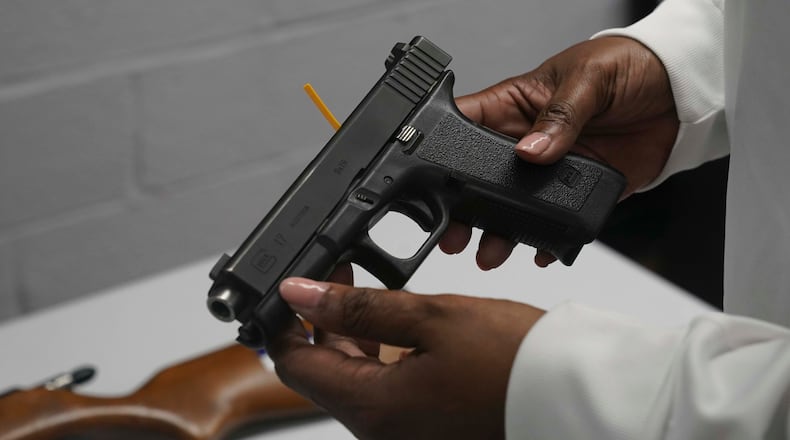 A handgun from a collection of illegal guns is reviewed during a gun buyback event, Saturday May 22, 2021 in Brooklyn, N.Y. Guns were handed over at the no-questions-asked event today, co-sponsored by state and county attorney generals and the NYPD, at the city-run Howard Houses residences. Individuals received pre-paid card payments of $25 up to $250 for firearms—with a bonus iPad for certain handguns or assault rifles. (AP Photo/Bebeto Matthews)