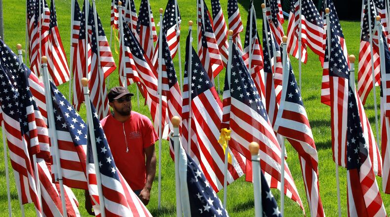 Rashad Whitaker, an employee of Natural Solutions Landscapes, takes a break from cutting grass to walk through the hundreds of American flags that make up the Field of Honor at Jackson, Lytle and Lewis Life Celebration Center Tuesday. This is the 10th year that the flags have been displayed at Jackson, Lytle and Lewis. The tribute to veterans will be on display until Flag Day on June 14. BILL LACKEY/STAFF