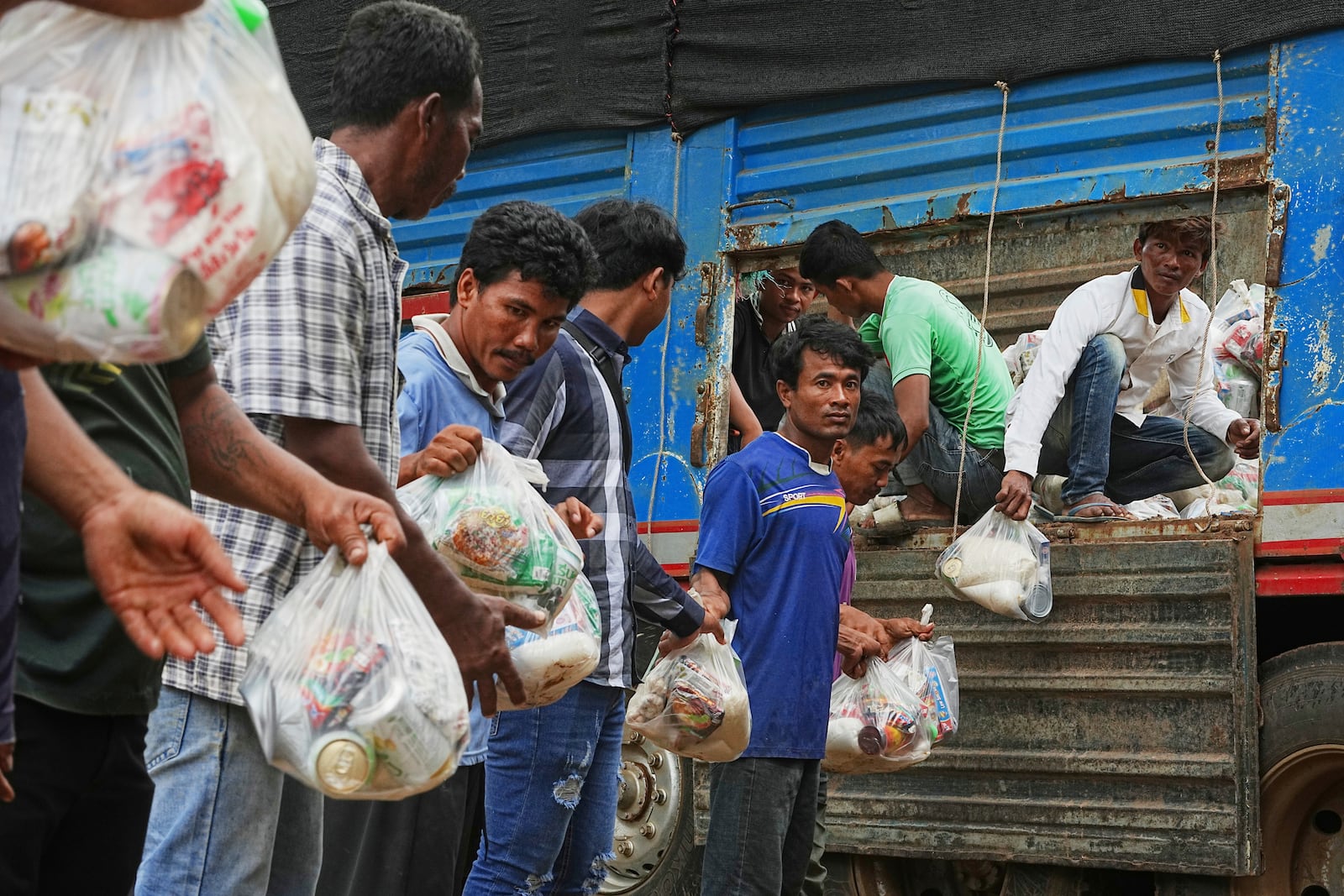 Local villagers help unloading supplies donated by a charity for refugees from a truck, as they take refuge in Wat Phnom Kamboar, Oddar Meanchey province, Cambodia, Sunday, July 27, 2025, amid the fighting between Thailand and Cambodia. (AP Photo/Heng Sinith)