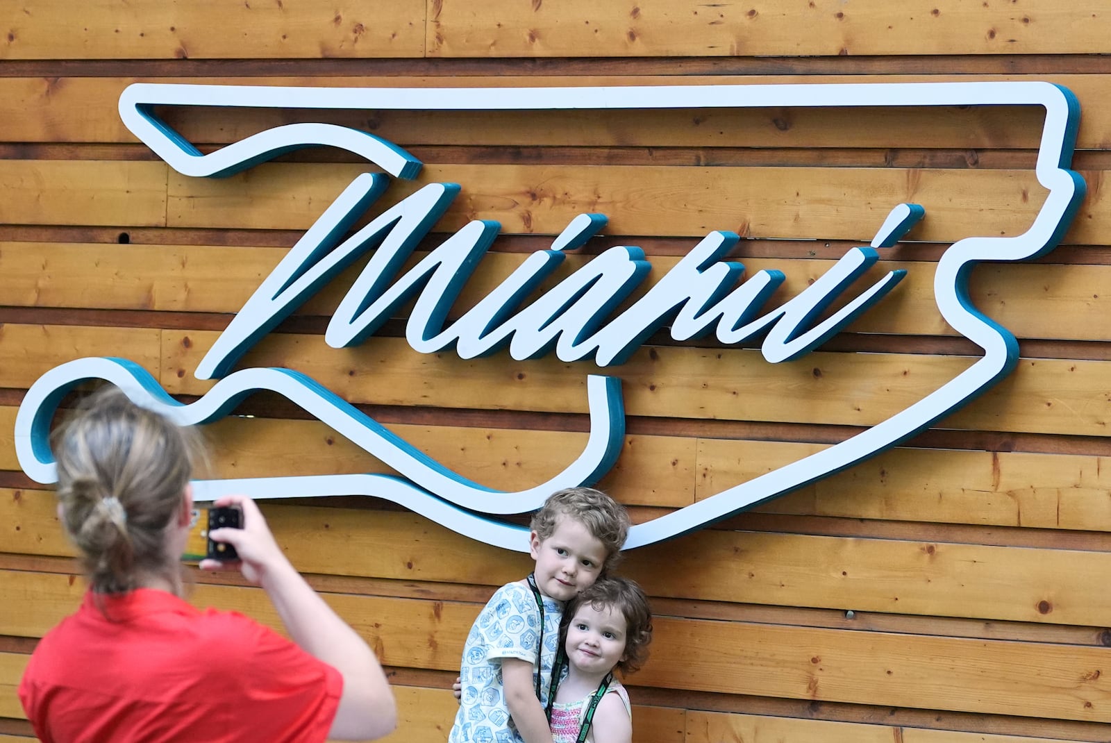 Aaron Mart, 4, and his sister Eloise, 2, whose father is an engineer for the Red Bull team, have their photo taken by their mother Anne Bachelay in front of a Formula One Miami Grand Prix auto race logo in the shape of the track, Thursday, May 1, 2025, in Miami Gardens, Fla. (AP Photo/Rebecca Blackwell)