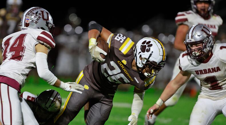 Kenton Ridge's Caleb Hall carries the ball between Urbana's Gio Torres, left, and Preston Wisma. BILL LACKEY/STAFF