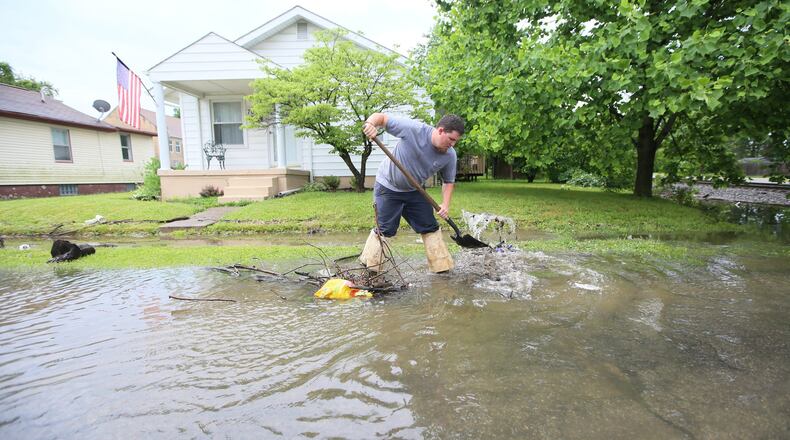 Hamilton city worker Colt Mann works to clear a storm drain along Kenworth Avenue after heavy rains caused flash flooding on the west side of Hamilton in 2016.