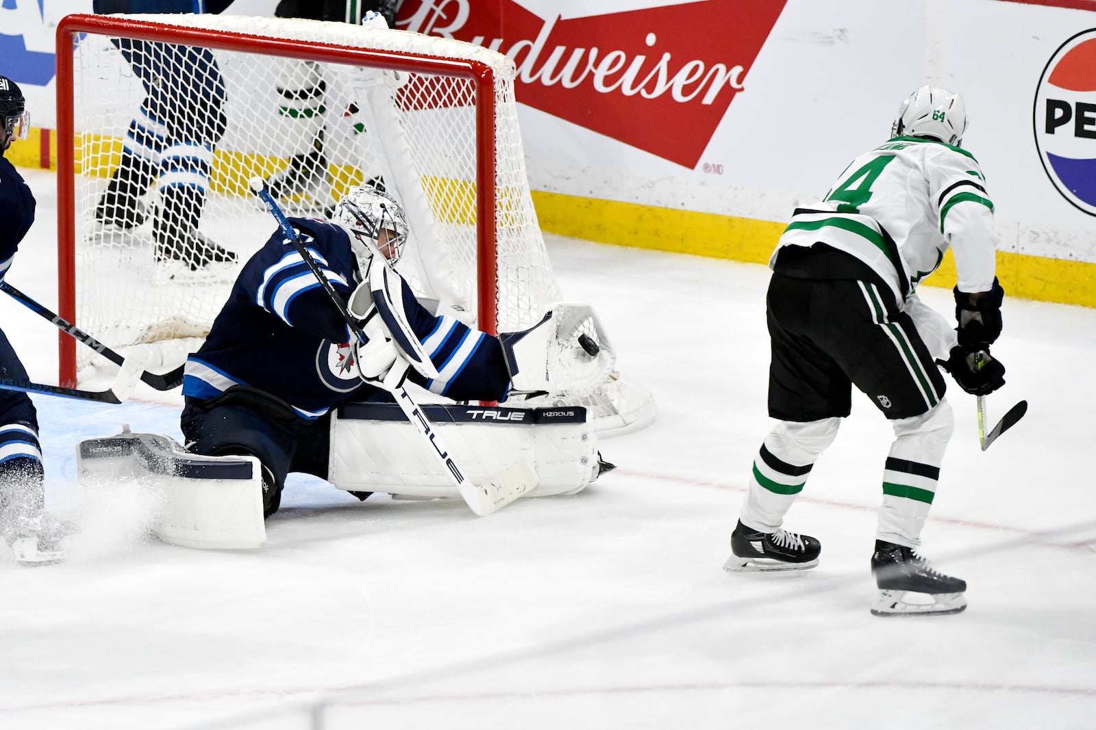 Winnipeg Jets goaltender Connor Hellebuyck (37) makes a save on Dallas Stars' Mikael Granlund (64) during third period NHL playoff hockey action in Winnipeg, Canada, Wednesday, May 7, 2025. (Fred Greenslade/The Canadian Press via AP)