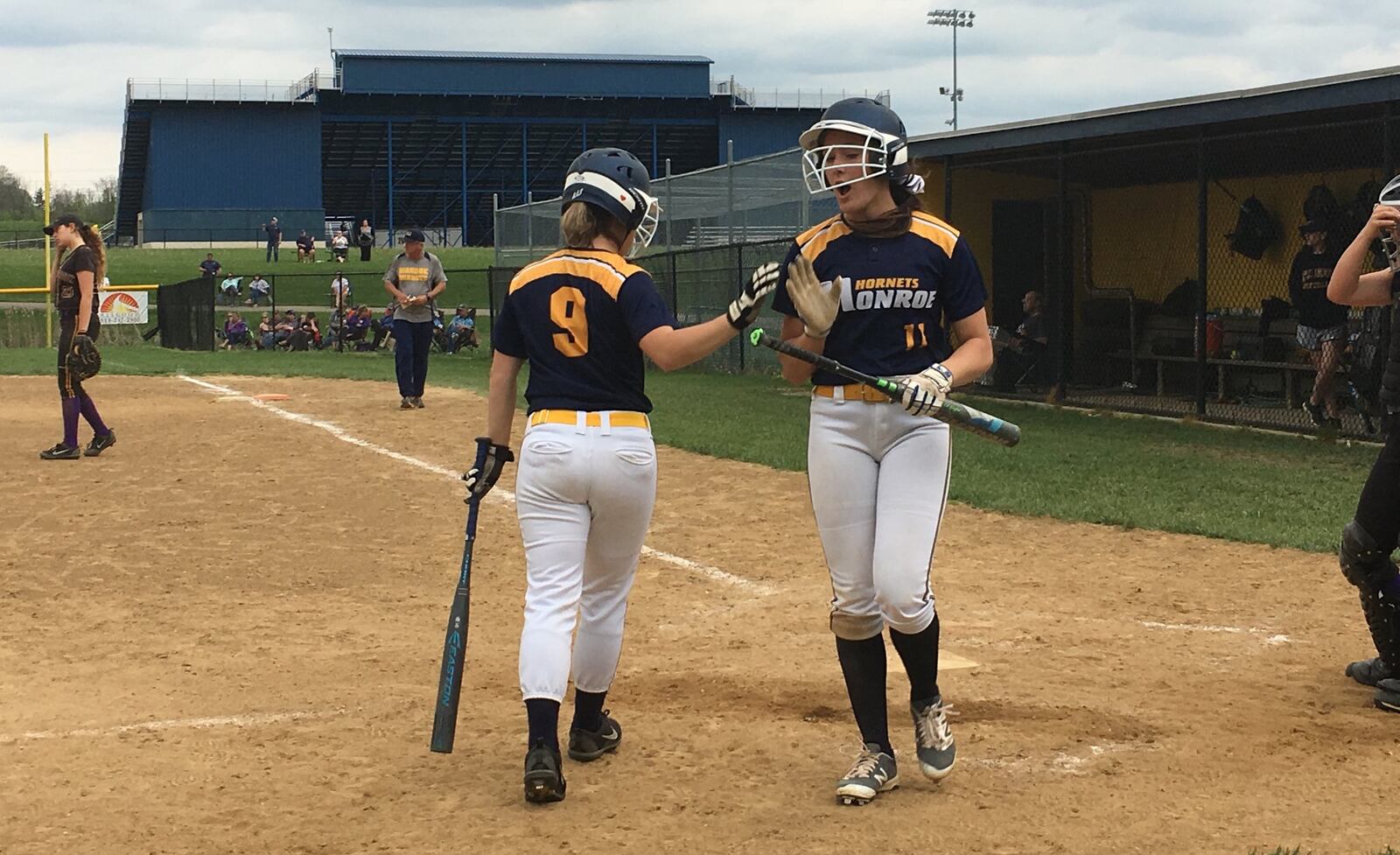 Monroe’s Faith Hensley (11) is congratulated by teammate Erin Dyke (9) after scoring a run during Thursday’s game against visiting Bellbrook. RICK CASSANO/STAFF