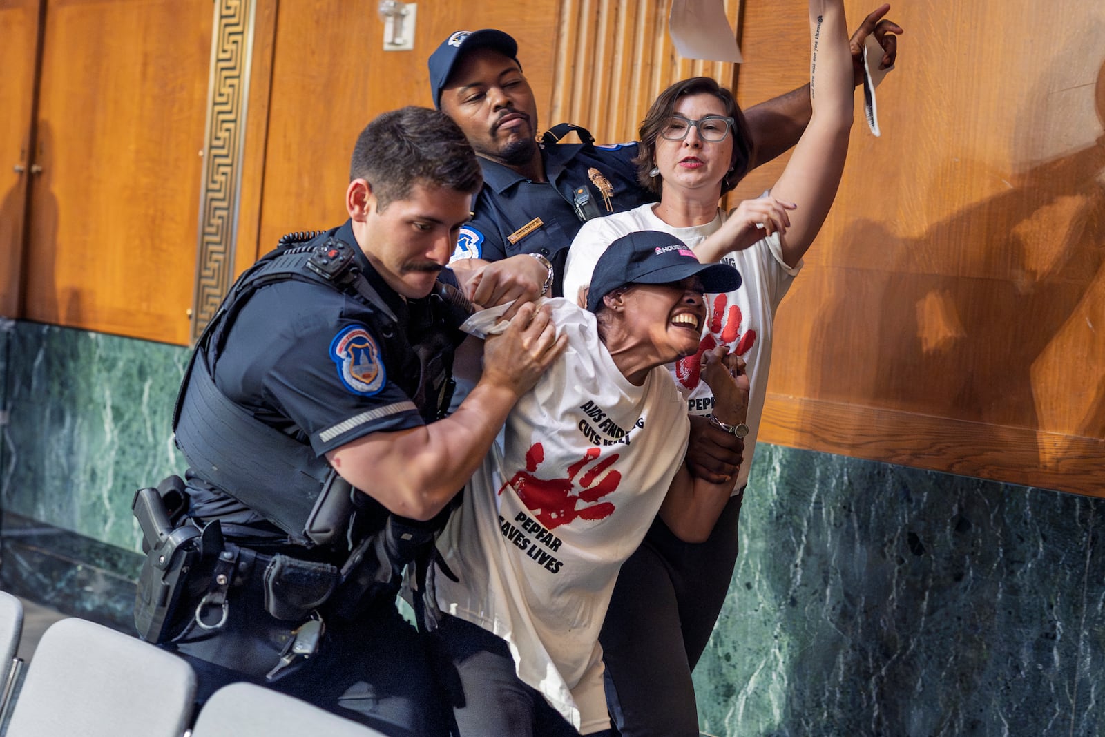 U.S. Capitol Police remove protesters after they began shouting in a Senate Appropriations Committee hearing as Office of Management and Budget director Russell Vought began to testify on the rescissions package, at the Capitol in Washington, Wednesday, June 25, 2025. (AP Photo/J. Scott Applewhite)