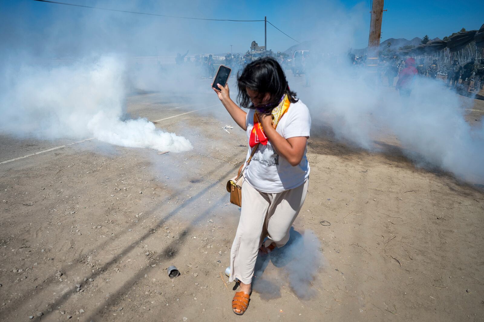 A protester runs from tear gas tossed by federal immigration agents to clear a path for the vehicles during a raid in the agriculture area of Camarillo, Calif., Thursday, July 10, 2025. (AP Photo/Michael Owen Baker)