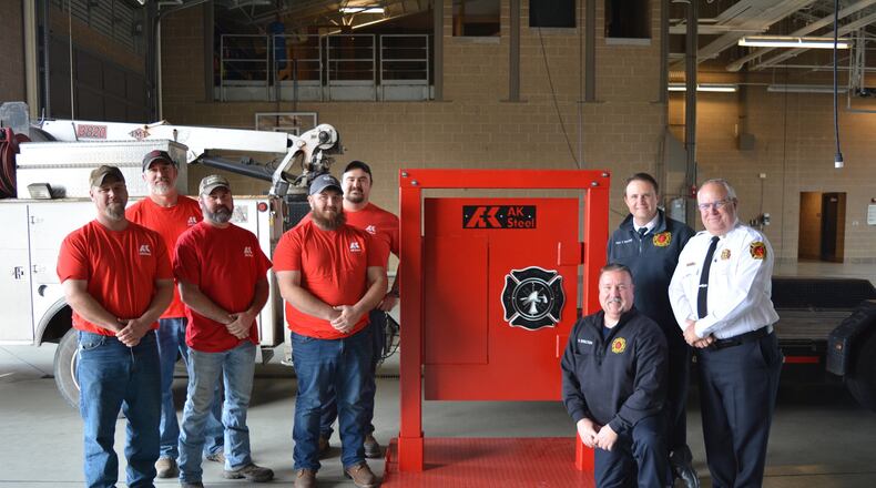 AK Steel representatives Brad Letsche, John Foster, Dan Lykins, Joe Rossi and Scott Brewer (left to right, left of door) donate and deliver a handmade fire training door to West Chester Fire Department on Dec. 12, 2019. On hand at Fire Headquarters, 9119 Cincinnati Dayton Road, to accept the door were Firefighter/Paramedic and Acting Lieutenant William Shelton (kneeling), Captain Troy Bonfield, and Assistant Chief David Pickering (left to right, right of door). CONTRIBUTED