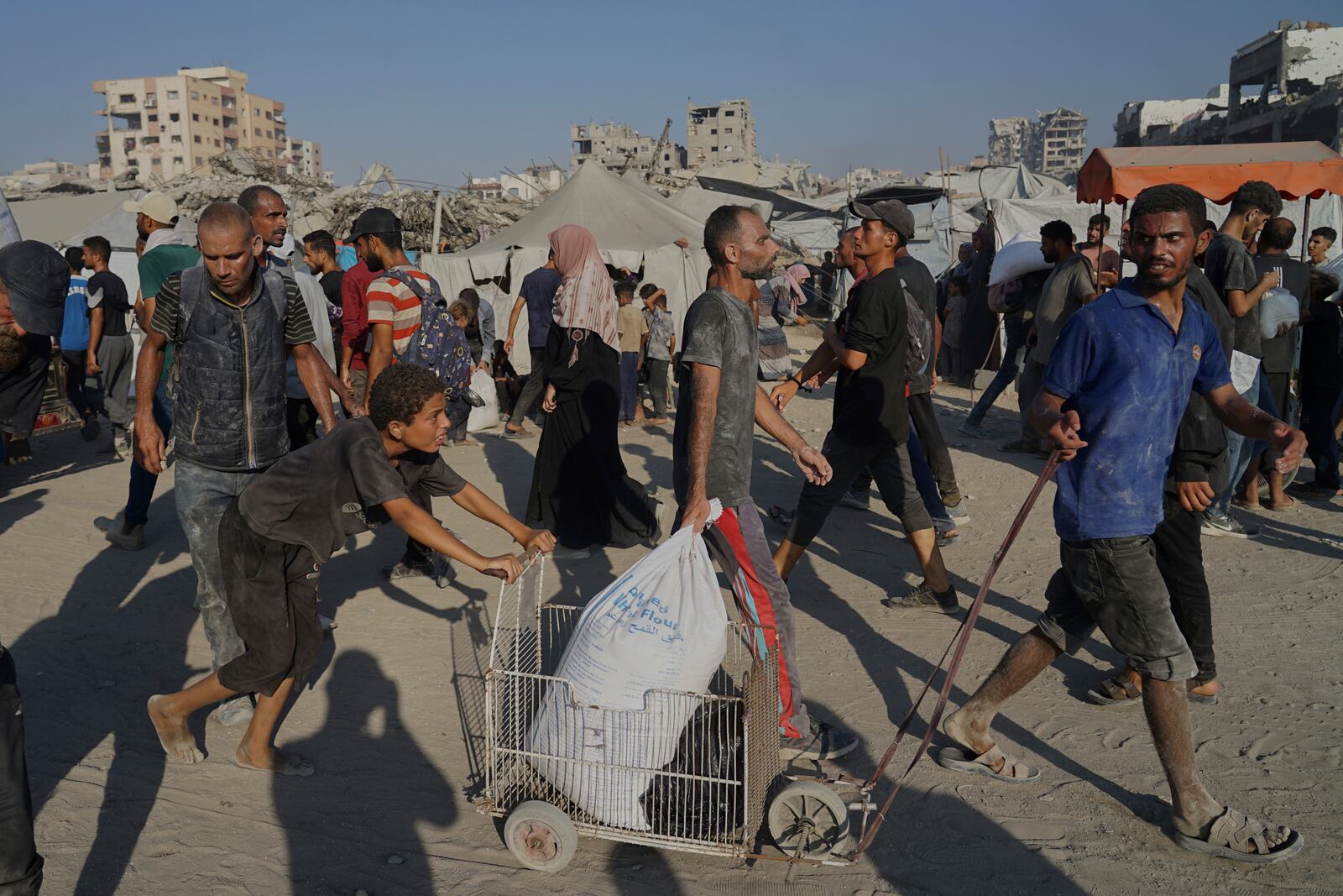 Palestinians carry sacks of flour unloaded from a humanitarian aid convoy that reached Gaza City from the northern Gaza Strip, Saturday, July 26, 2025. (AP Photo/Jehad Alshrafi)