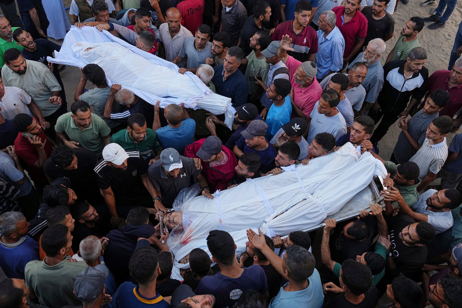 Palestinians carry the bodies of relatives who were killed in an Israeli military strike on Gaza, at Al-Shifa Hospital in Gaza City, Thursday, June 19, 2025. (AP Photo/Jehad Alshrafi)