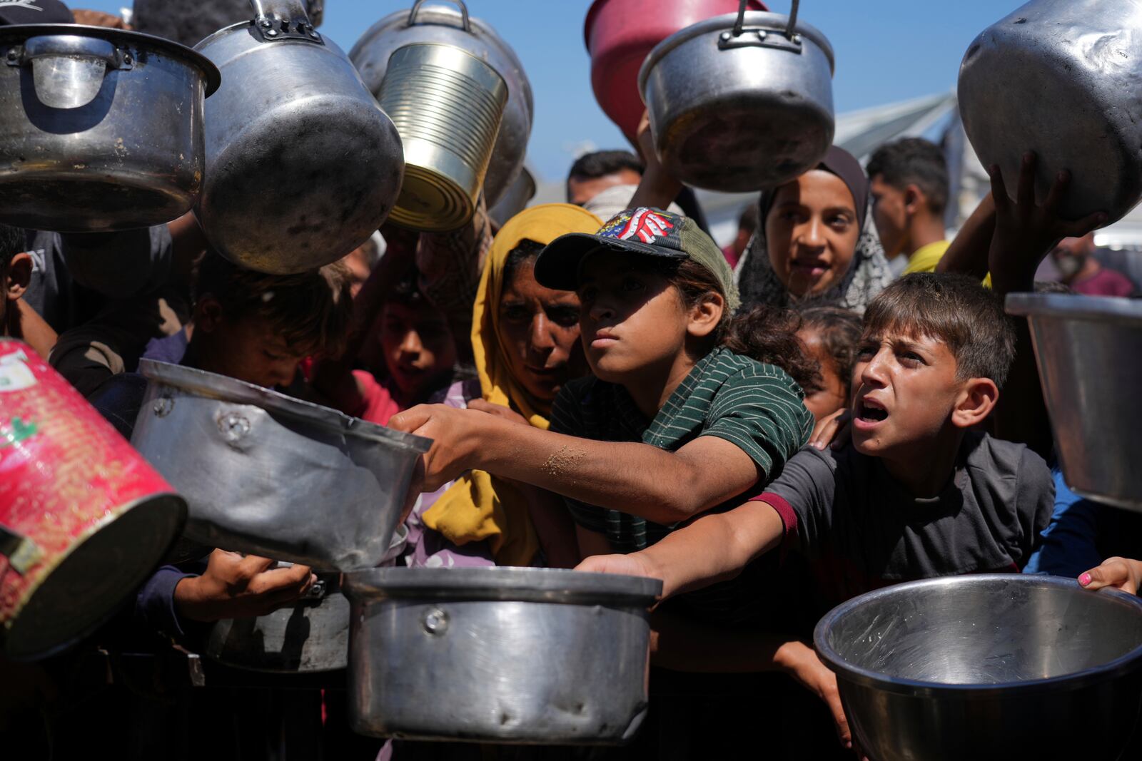Palestinians struggle to get donated food at a community kitchen in Khan Younis, southern Gaza Strip, Monday, June 2, 2025. (AP Photo/Abdel Kareem Hana)