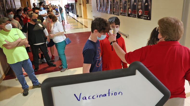 Suzanne Massie, takes temperatures before people enter the COVID vaccination clinic at Tecumseh High School. BILL LACKEY/STAFF