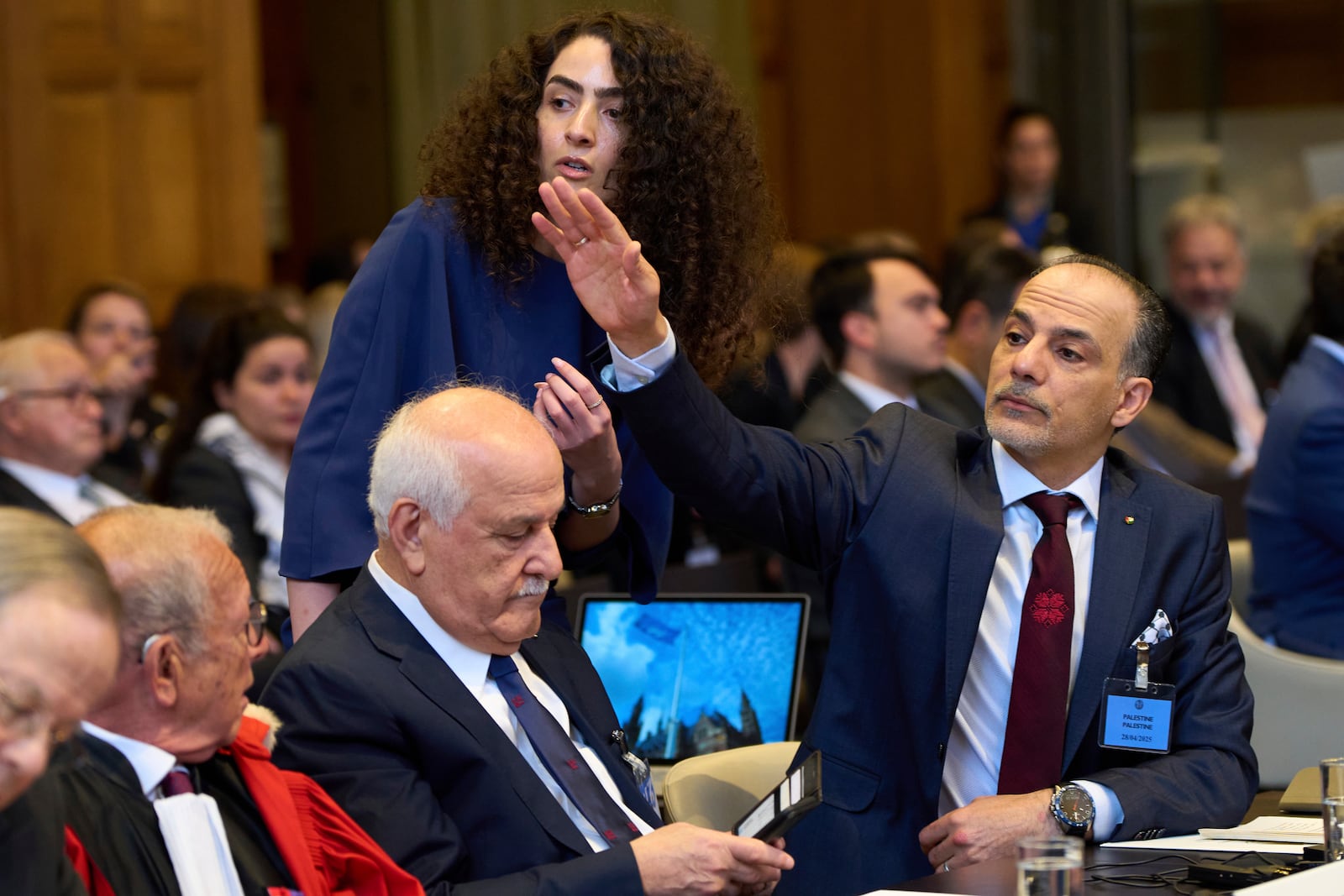 Palestinian Ambassadors to the United Nations Ammar Hijazi, right, and Riyad Mansour, center seated, and other members of the legal team wait for the International Court of Justice to open hearings into a United Nations request for an advisory opinion on Israel's obligations to allow humanitarian assistance in Gaza and the West Bank, in The Hague, Netherlands, Monday, April 28, 2025. (AP Photo/Peter Dejong)