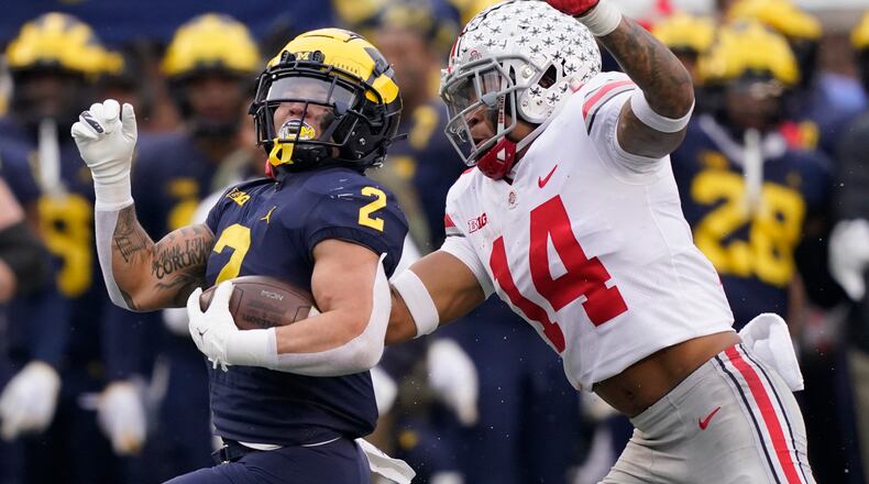 Michigan running back Blake Corum (2) is chased by Ohio State safety Ronnie Hickman (14) during the second half of an NCAA college football game, Saturday, Nov. 27, 2021, in Ann Arbor, Mich. (AP Photo/Carlos Osorio)