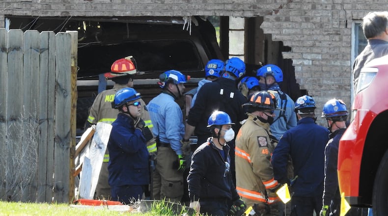 Emergency units work to remove a truck that slammed into a Monroe house this morning NICK GRAHAM/STAFF