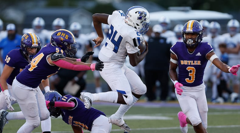 Xenia's Deaute White leaps over a  Butler player as he carries the ball. BILL LACKEY/STAFF