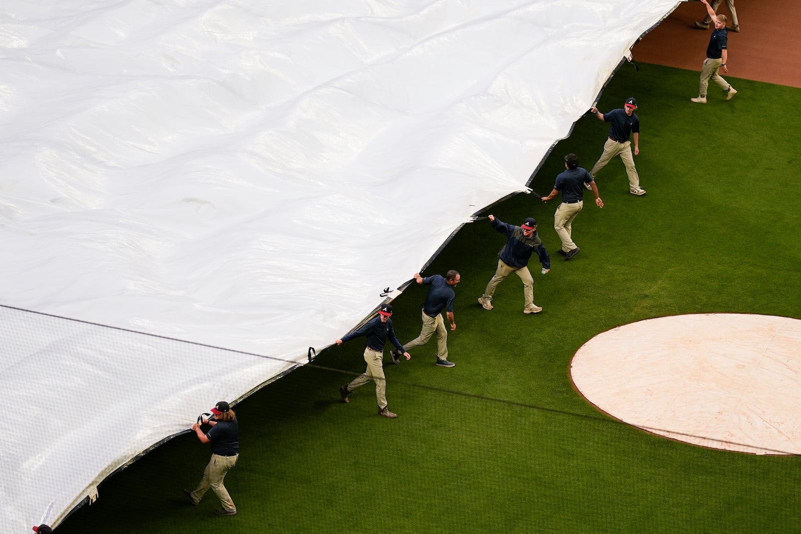 Crews cover the field before a rain-delayed baseball game between the Atlanta Braves and the Los Angeles Dodgers, Saturday, May 3, 2025, in Atlanta. (AP Photo/Mike Stewart)
