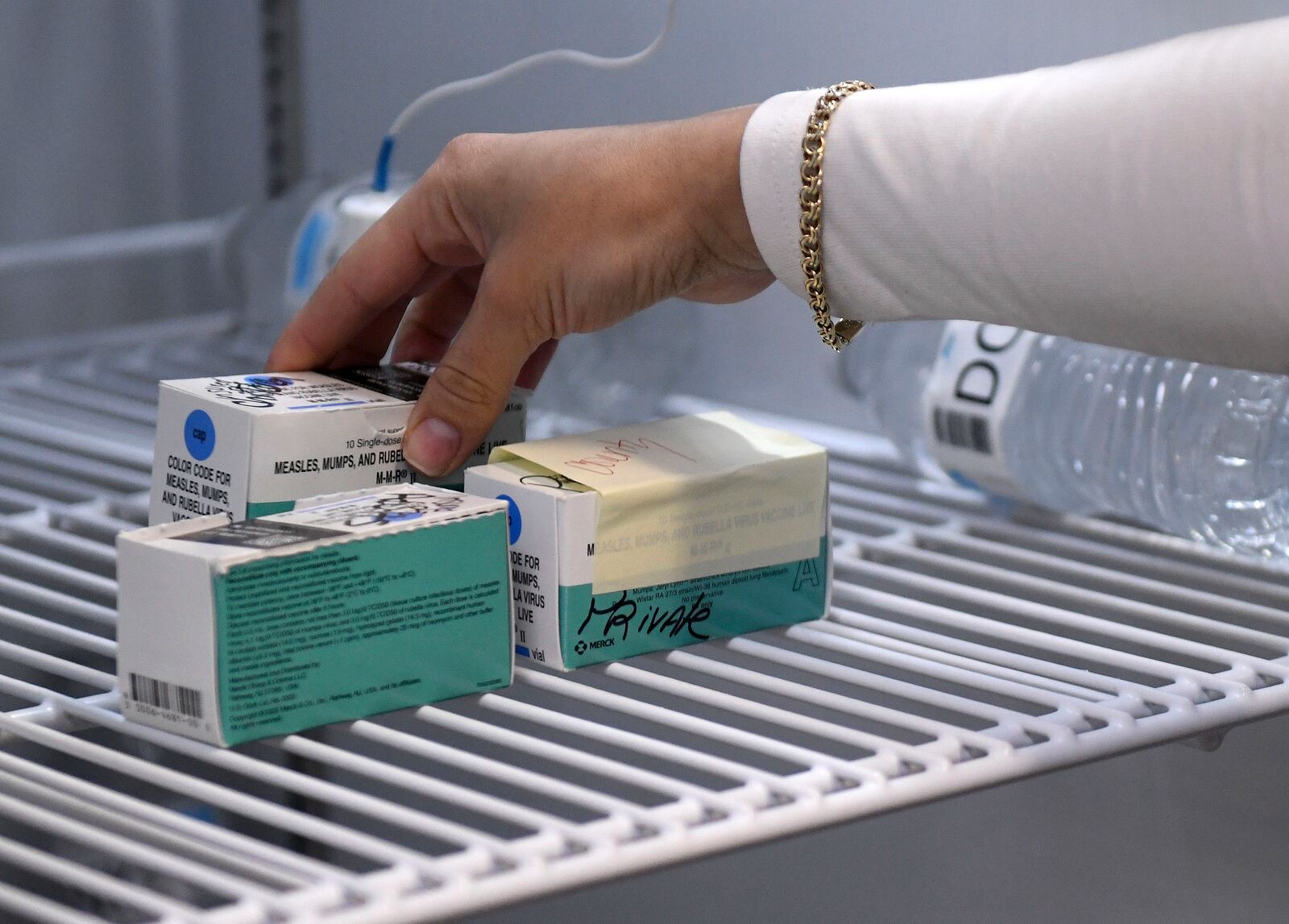Anna Hicks places the measles, mumps and rubella vaccine in a refrigerator at the Andrews County Health Department's measles clinic, Tuesday, April 8, 2025, in Andrews, Texas. (AP Photo/Annie Rice)