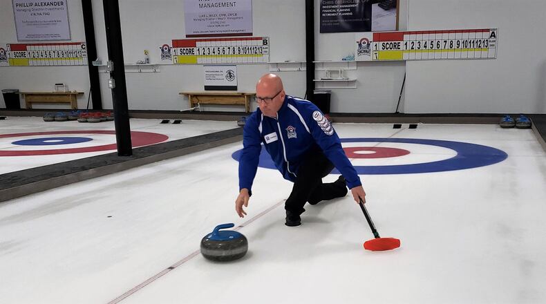 Jonathan Penney, president of the Cincinnati Curling Club, slides a stone down the ice toward concentric circles known as “the house” in a demonstration of the sport. The Cincinnati Curling Club is opening the first dedicated curling only facility in the tri-state area at 5150 Duff Drive in West Chester Twp. The former warehouse includes three lanes. ERIC SCHWARTZBERG/STAFF